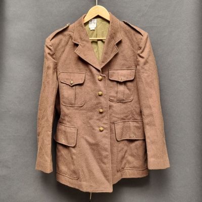 une veste marron suspendue à un cintre contre un mur gris