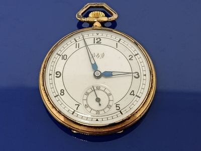 un gros plan d'une montre de poche posée sur une surface bleue