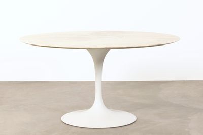 une table ronde avec un piètement blanc et un plateau en bois