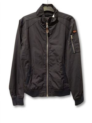 La veste est noire et comporte une fermeture éclair sur le devant.