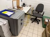 un bureau avec une imprimante et une chaise dans une pièce