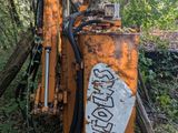 a rusted orange machine sitting in the middle of the woods