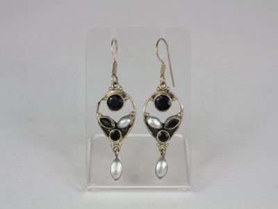 a pair of black and white earrings on a clear display case