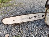 a chainsaw sitting on the ground on a gravel road