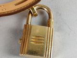 a gold padlock on a brown leather strap