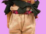 une poupée qui porte un chapeau de paille et un pantalon