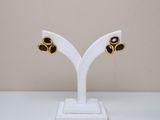 a close up of a pair of black and gold earrings on a white stand