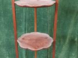 a three tiered wooden shelf with a green curtain in the background