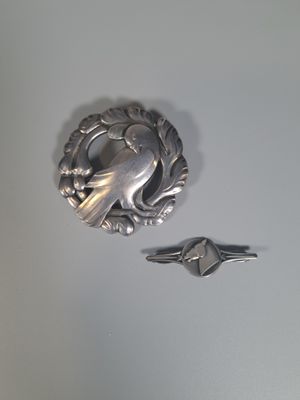 une broche en forme d'oiseau en argent et une bague en argent posées sur une table