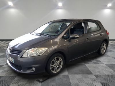 La voiture grise est garée dans le garage, sur le sol à damier.