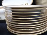 a stack of plates with gold rims on a black table