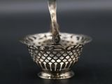 an antique silver bowl with a handle on a black surface