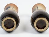 pair of black and gold vases on a white surface