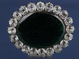 une image représentant une broche verte et blanche entourée de diamants