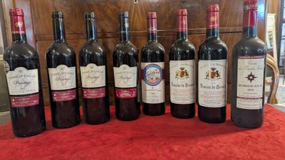 several bottles of wine are lined up on a red cloth