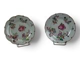 pair of porcelain plates with floral designs on them on a white surface