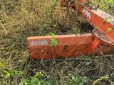 a rusted orange machine sitting in the middle of a field