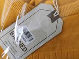 a yellow sweater with a price tag attached to it