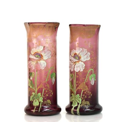 une paire de vases roses ornés de fleurs, posés sur une surface blanche