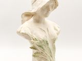 a close up of a statue of a woman with a hat on
