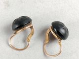 pair of gold and black stone earrings on a white surface