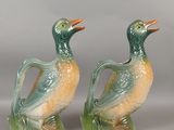 une paire de canards verts et orange posés sur un socle vert