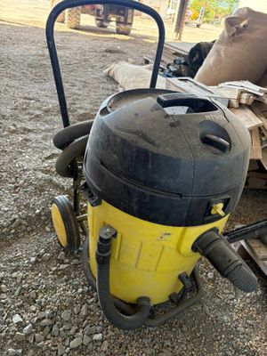 un aspirateur jaune et noir posé par terre à côté d'un tas de bois
