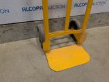 a yellow hand truck that is sitting in front of a wall