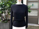 un pull noir et blanc posé sur un mannequin devant une porte