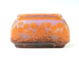 purple and orange vase with orange flowers on it on a white surface
