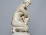 marble statue of a woman kneeling on a marble pedestal