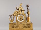 a gold clock with a statue of a woman sitting on top of it