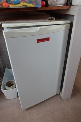 un petit réfrigérateur blanc dans le coin d'une pièce