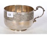 une coupe ancienne en argent, munie d'une poignée et de deux anses, sur fond blanc
