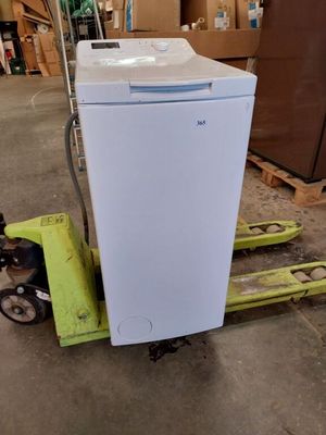 un réfrigérateur blanc posé sur une palette dans un entrepôt