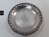 an antique silver plate on a white table with a black label