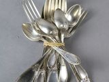 a bunch of silver spoons and forks wrapped in a ribbon