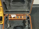 une mallette orange posée par terre, contenant des outils