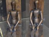 deux statues en bronze représentant une personne assise sur un banc