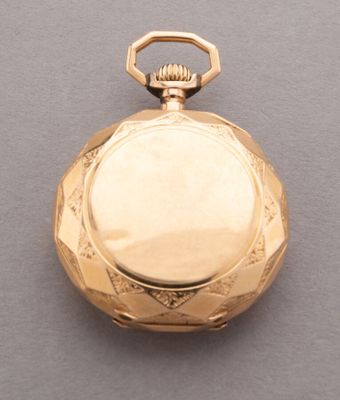 une image représentant une montre de poche en or posée sur une surface grise