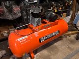 an orange air compressor sitting in a garage with other tools