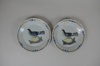 deux assiettes ornées d'oiseaux peints, posées sur une table