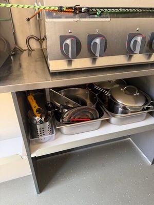 des casseroles et des poêles sont posées sur une étagère dans une cuisine