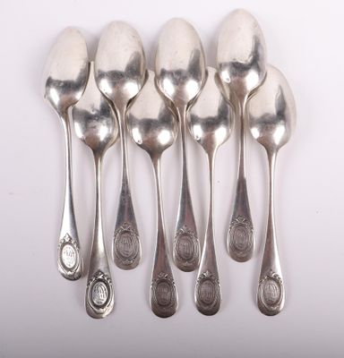 six silver spoons are lined up in a row on a white surface