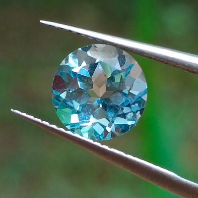un gros plan d'un diamant bleu tenu par une pince