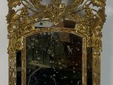 un cadre doré sur lequel est posé un miroir, posé sur une table