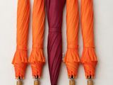 four umbrellas are lined up against a white wall with a wooden handle