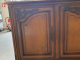a wooden cabinet in a room with a lot of windows