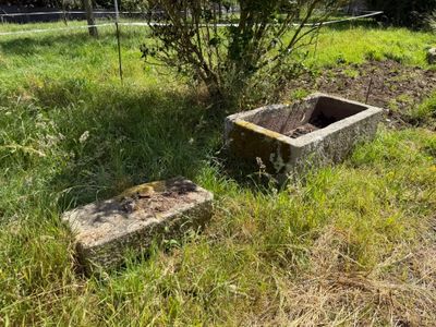 un abreuvoir en pierre posé au milieu d'un champ herbeux