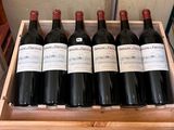 six bottles of wine in a wooden box on a table